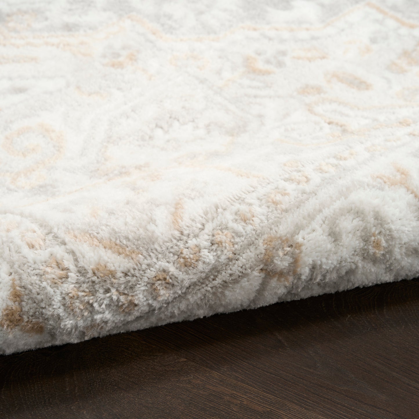 Cream and beige geometric shag rug with plush pile on dark wood floor.