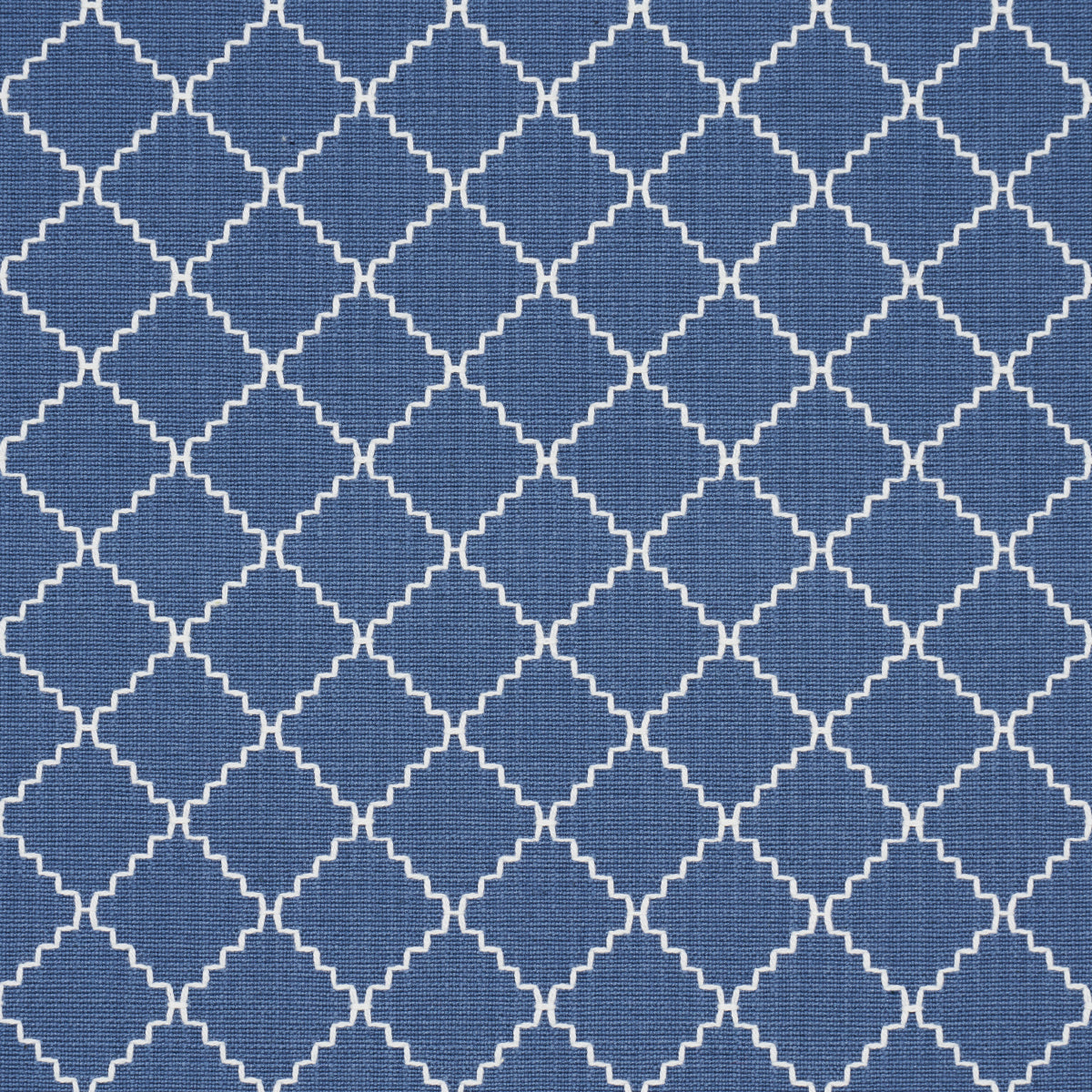 Blue fabric with white interlocking quatrefoil lattice woven textile for upholstery or curtains.