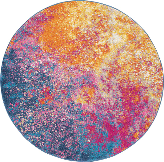 Round placemat with vibrant powder-splatter pattern in orange, pink, yellow, teal and blue; modern colorful table accessory.