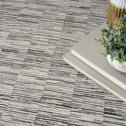 Beige-gray geometric rug with stacked neutral books, a small potted succulent, and a gold vase in a chic home decor scene.