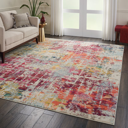 Abstract multicolor area rug in pink, orange, teal and beige tones on a dark wood floor beside a cream sofa.