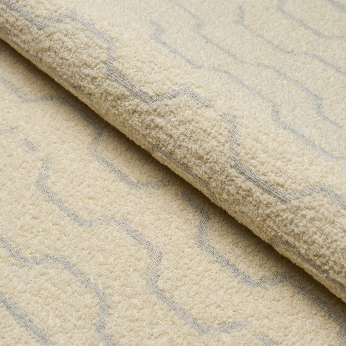 Cream shag rug with light gray zigzag pattern and plush pile, rolled edge showing texture.