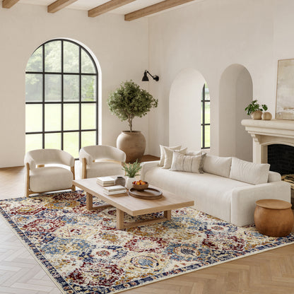 Neutral living room with arched window, beige sofa, two cream armchairs, wooden coffee table, lush plant, colorful rug.