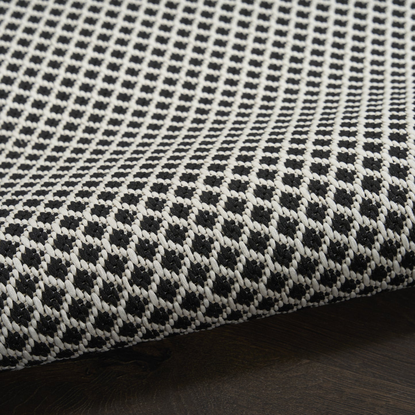 Close-up of black and white woven rug runner with a dotted geometric pattern and a visible seam edge.