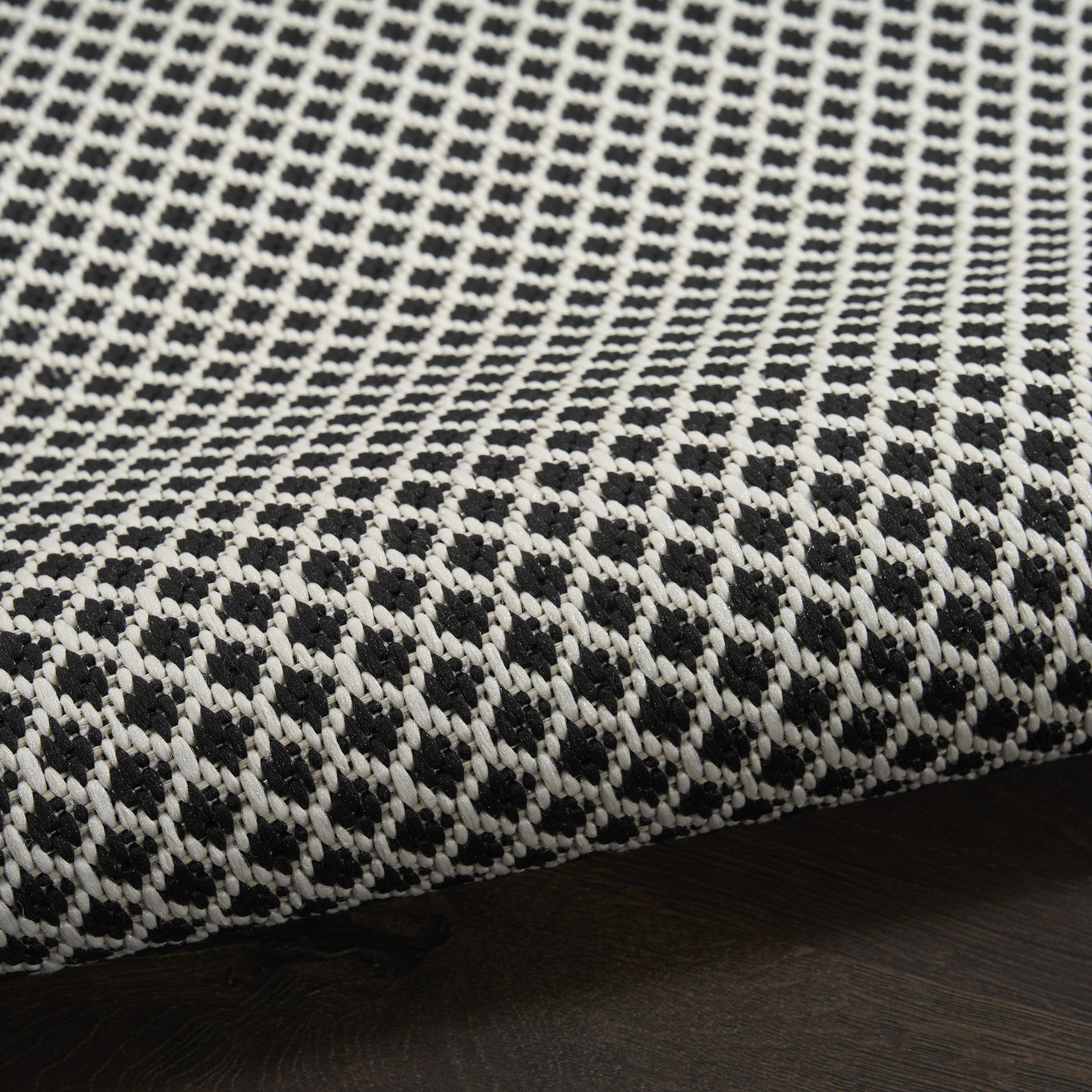 Close-up of black and white woven rug runner with a dotted geometric pattern and a visible seam edge.
