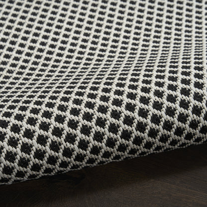 Close-up of black and white woven rug runner with a dotted geometric pattern and a visible seam edge.