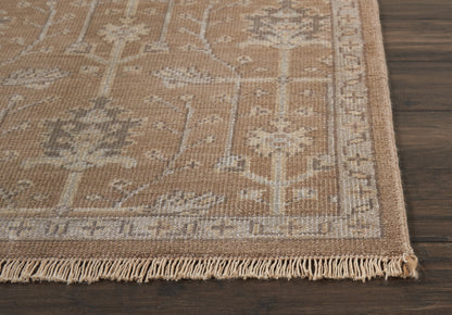 Beige oriental rug with floral border and tassel fringe on dark wood floor.