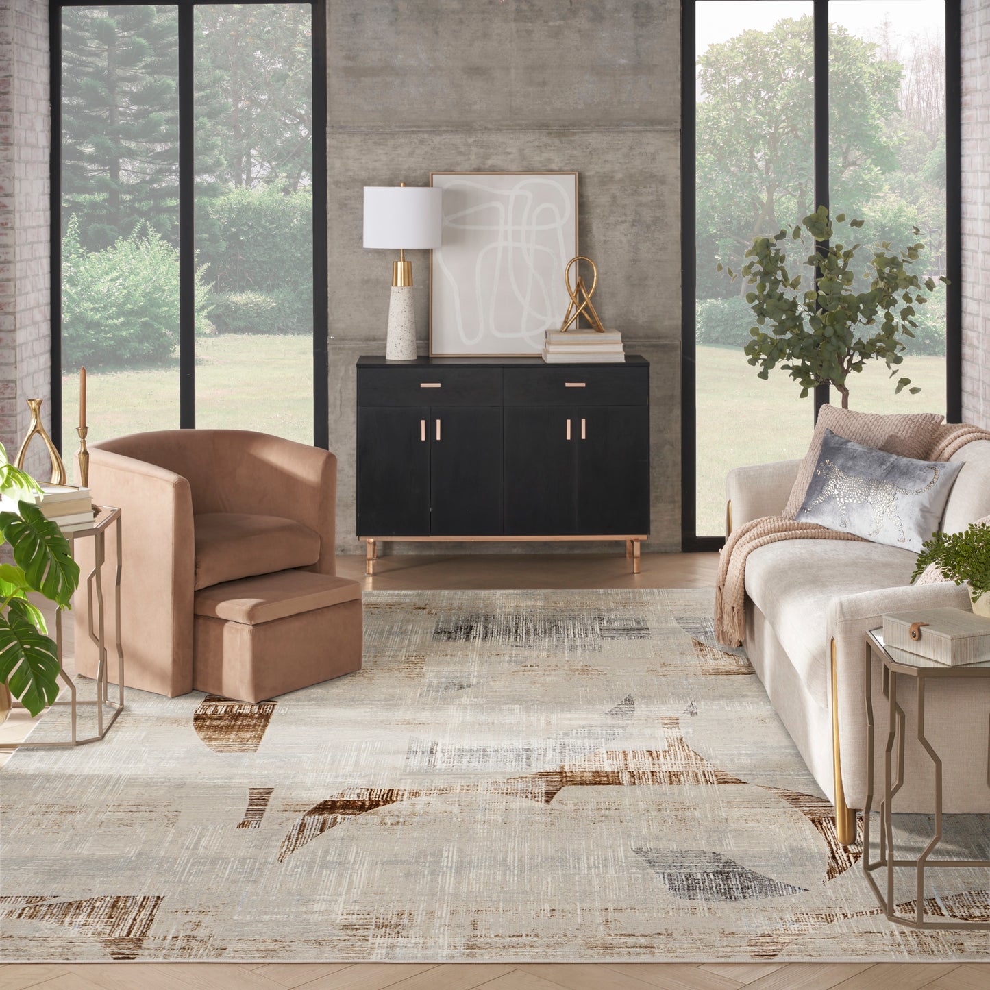 Modern living room with black sideboard featuring gold handles, tan leather chair, beige sofa, abstract neutral rug.