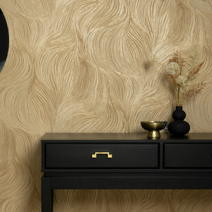 Black two-drawer console with gold handle, gold bowl, black vase and dried stems against gold textured wallpaper.