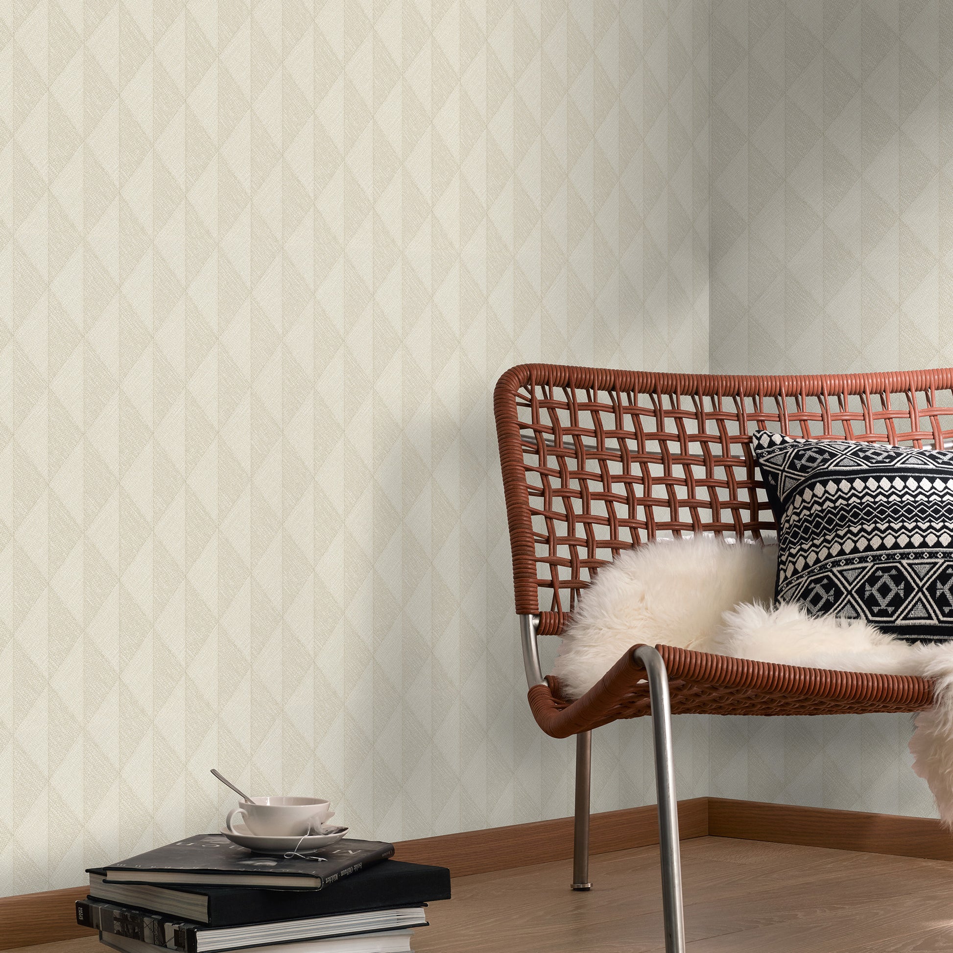Brown wicker chair with fluffy white throw and black-and-white patterned cushion, wood floor; books and teacup nearby.