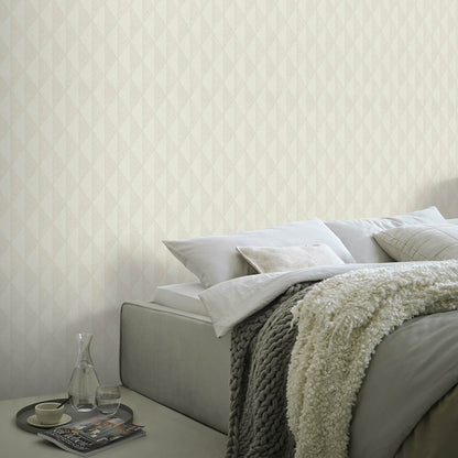 Neutral bedroom with taupe wallpaper on the walls, a gray upholstered bed, cream knit throw, white pillows, and a glass carafe & cup on a tray.