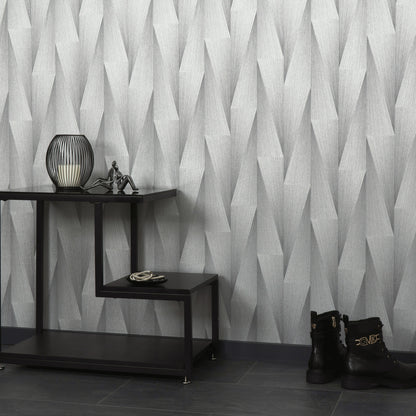 Geometric gray wallpaper behind a black stepped console table with a lantern lamp, small figurine, rope coil, and black buckle ankle boots on dark tile.