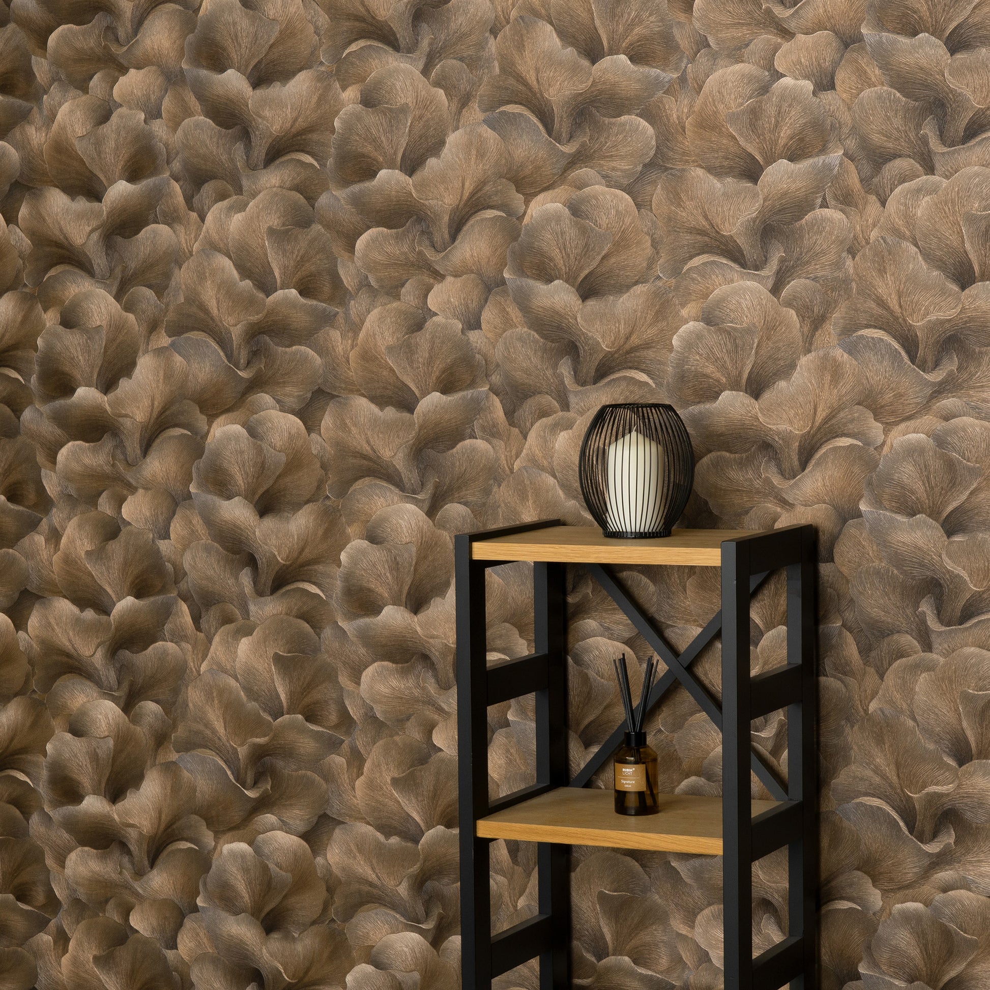 Brown floral-pattern wallpaper backdrop with a black metal-and-wood shelf, lantern on top, diffuser bottle on lower shelf.
