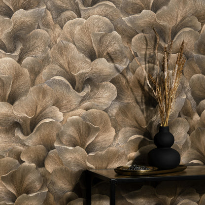 Brown floral wallpaper with oversized, soft-textured leaves; black matte vase and dried grasses on a dark console table.