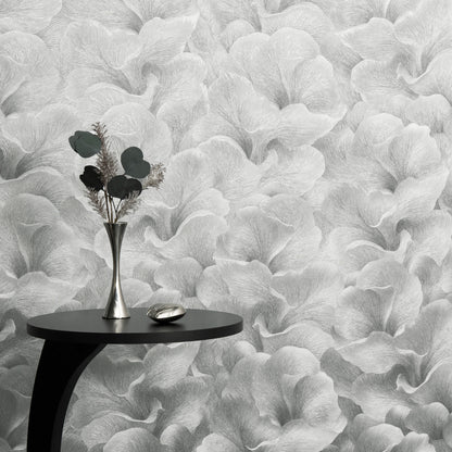 Black round side table with curved leg, silver vase of dried greenery & a metallic dish against grey botanical wallpaper.