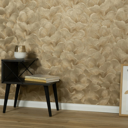 Beige Floral Glow Gold wallpaper on the wall behind a black side table holding books and a white vase with a gold lid; a framed artwork leans against the wall.