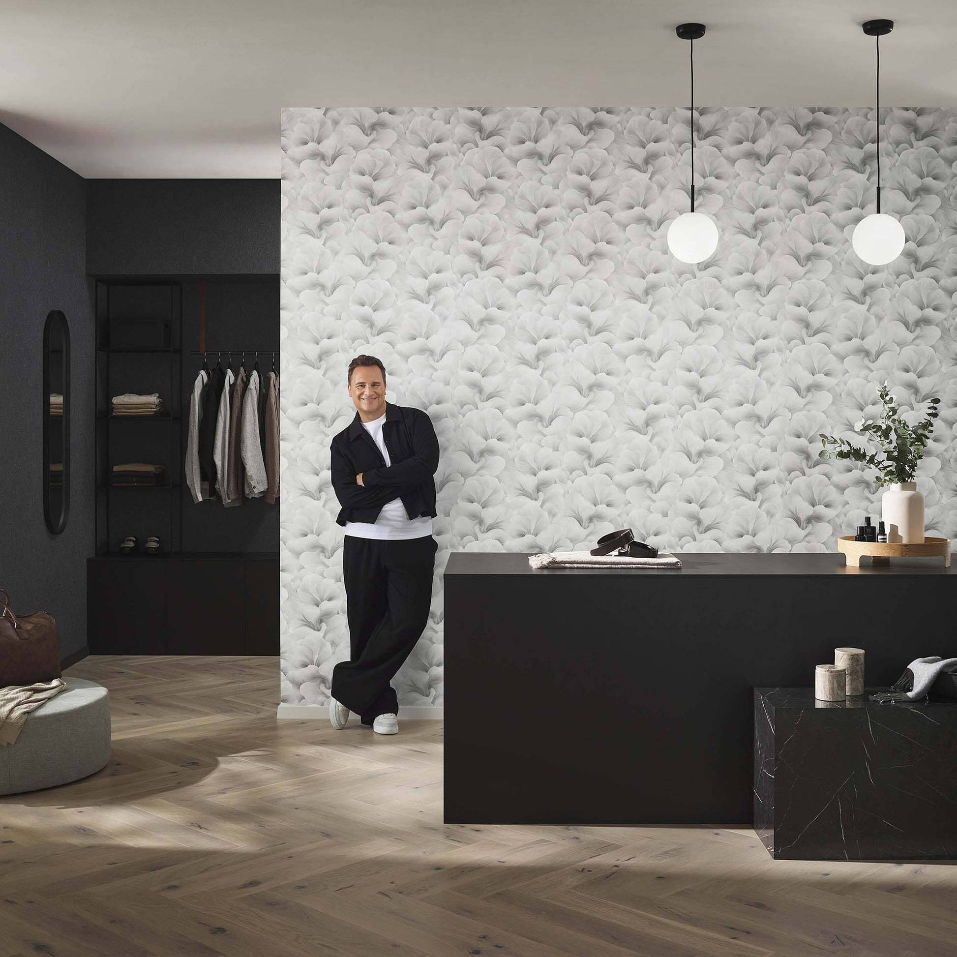 Modern boutique with black desk, gray wallpaper, globe pendant lights, wooden floor; person in black near counter.