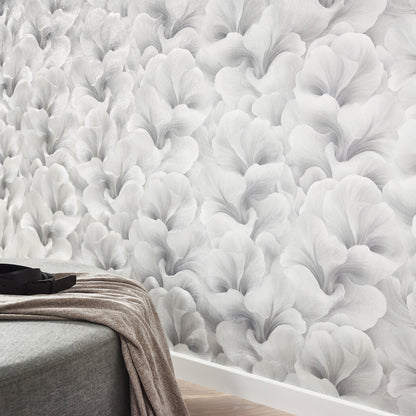 Gray floral wallpaper with large petal shapes, shown behind a gray upholstered bed.