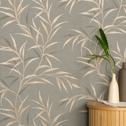 Brown wallpaper with beige botanical leaves; round wooden table with a cream vase, green plant stem, and a brown bottle.