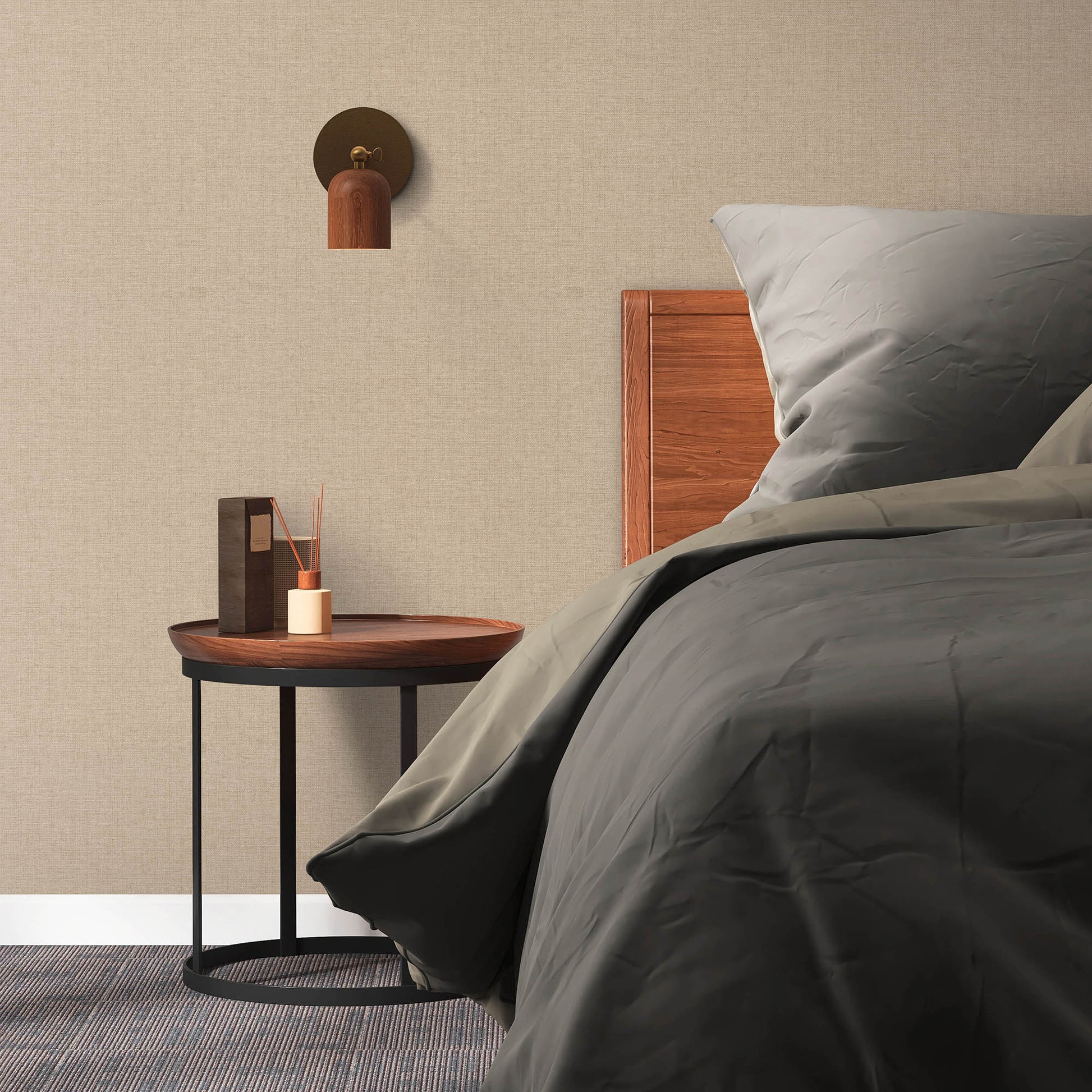 Beige textured wall, wooden headboard, gray bedding; round side table with black legs and a wall sconce.