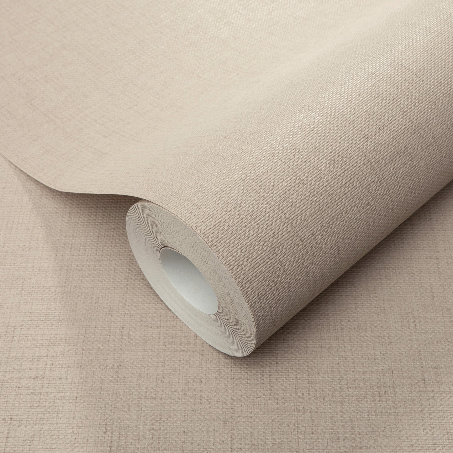 Beige wallpaper roll with woven texture and white inner core on a beige surface.