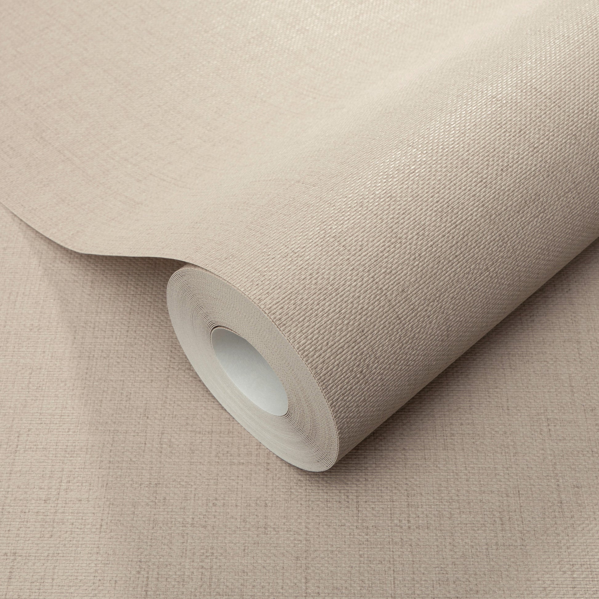 Beige wallpaper roll with woven texture and white inner core on a beige surface.