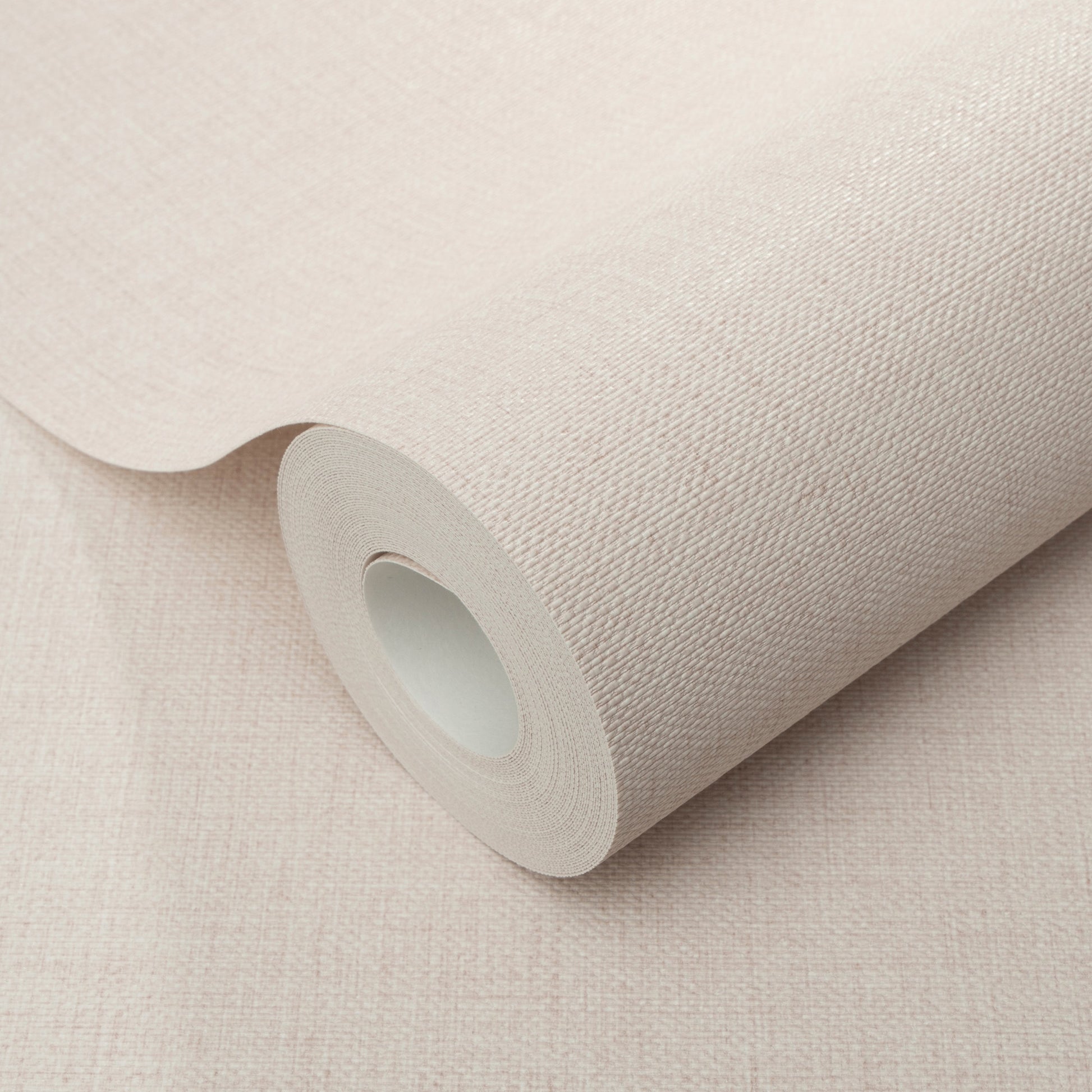 Pink jute-texture wallpaper roll with a cardboard core, partially unrolled.