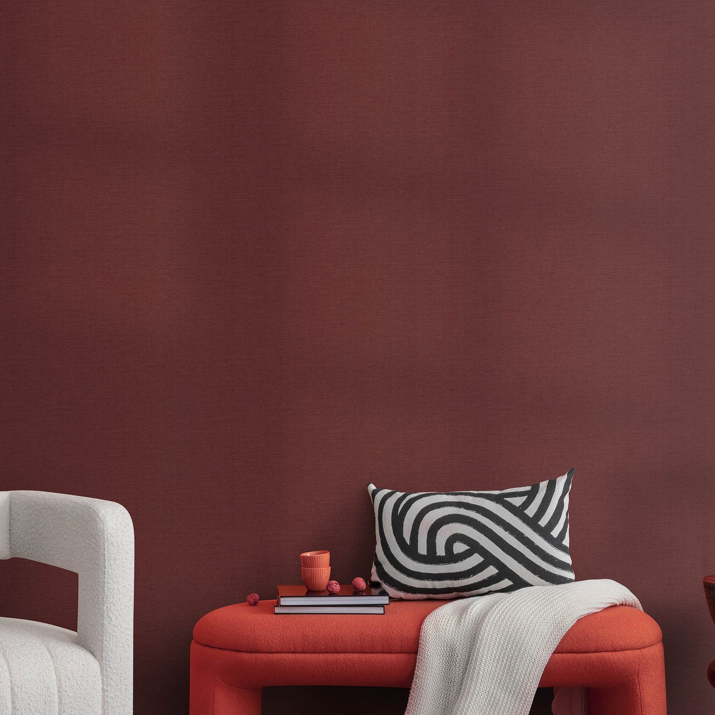 Red wallpaper with a jute texture and an abstract traditional pattern.