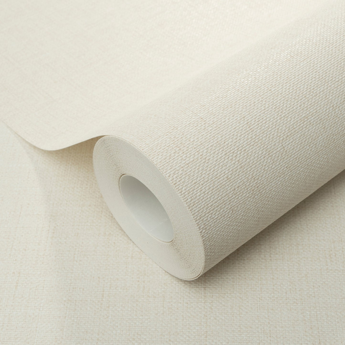 Cream jute-texture wallpaper roll on beige surface, fabric-like pattern with white inner core
