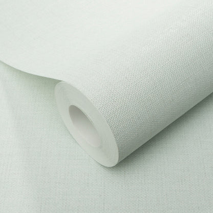 Teal wallpaper roll with visible jute texture, partially unrolled on a pale surface.
