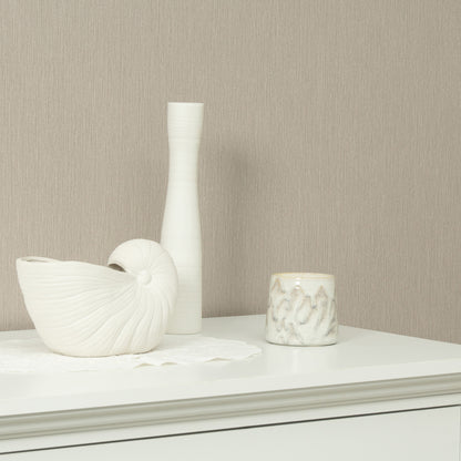 White ceramic vase, shell-like sculpture, and marble-pattern candle on a white dresser against beige wall.