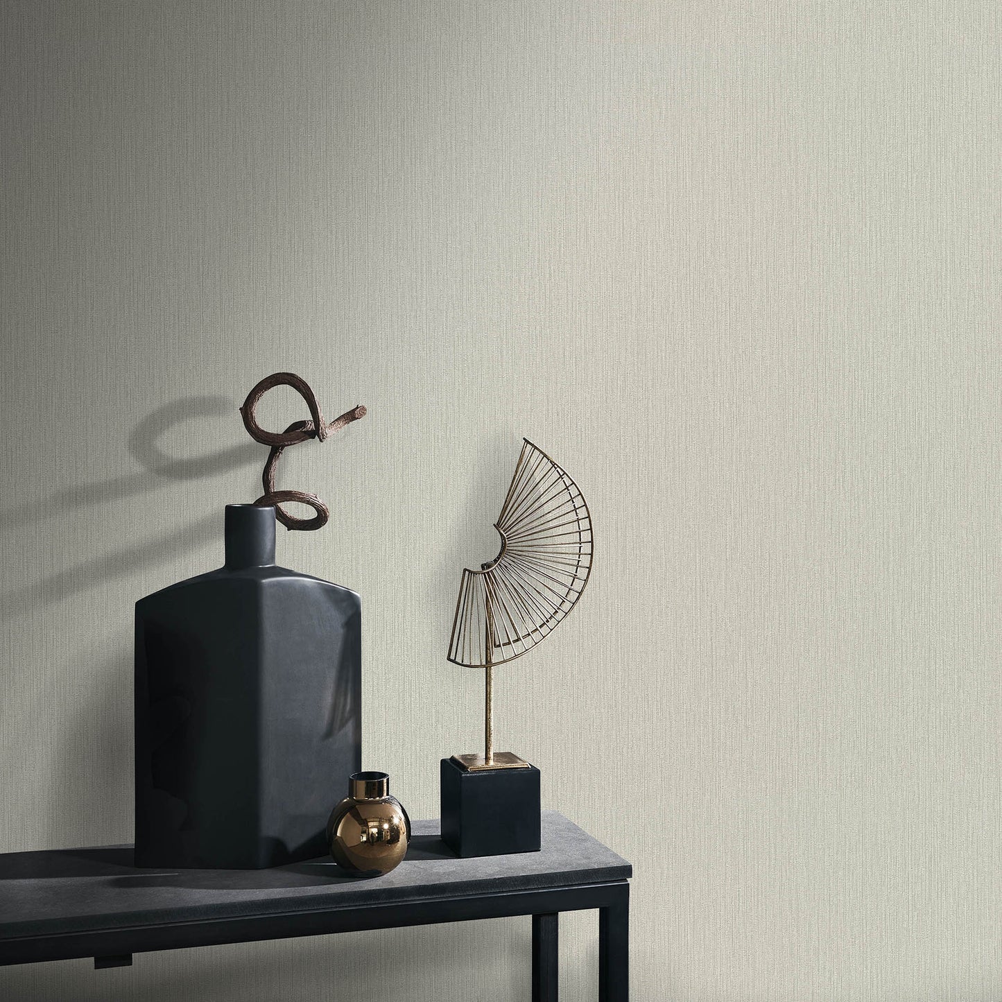 Matte blue geometric vase with a spiraled metal accent, small gold orb, and wire fan sculpture on a dark console table.