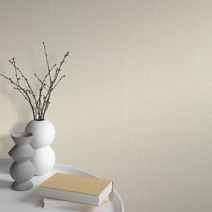 Minimalist white spherical vase with bare branches beside stacked gray ceramic vases and beige books on a white tray.