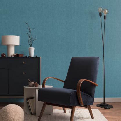 Mid-century navy blue fabric lounge chair with curved wooden arms and tapered legs in a modern living room.