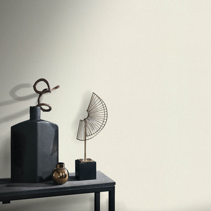 Matte charcoal bottle with looped rope, brass orb, and a wire fan sculpture on a dark shelf—minimalist decor.