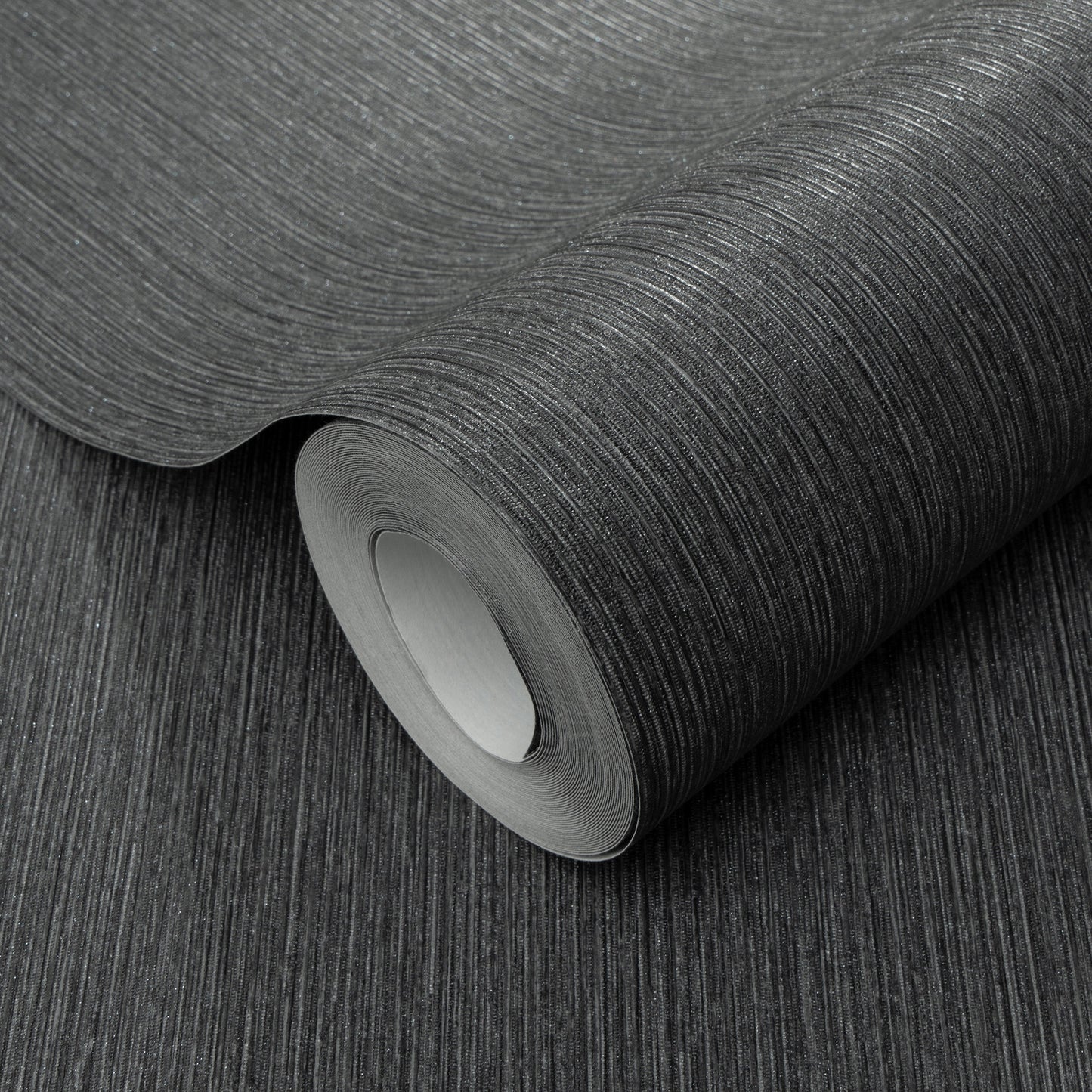 Charcoal textured wallpaper roll with subtle vertical linear grain, matte finish, partially unrolled for home decor.