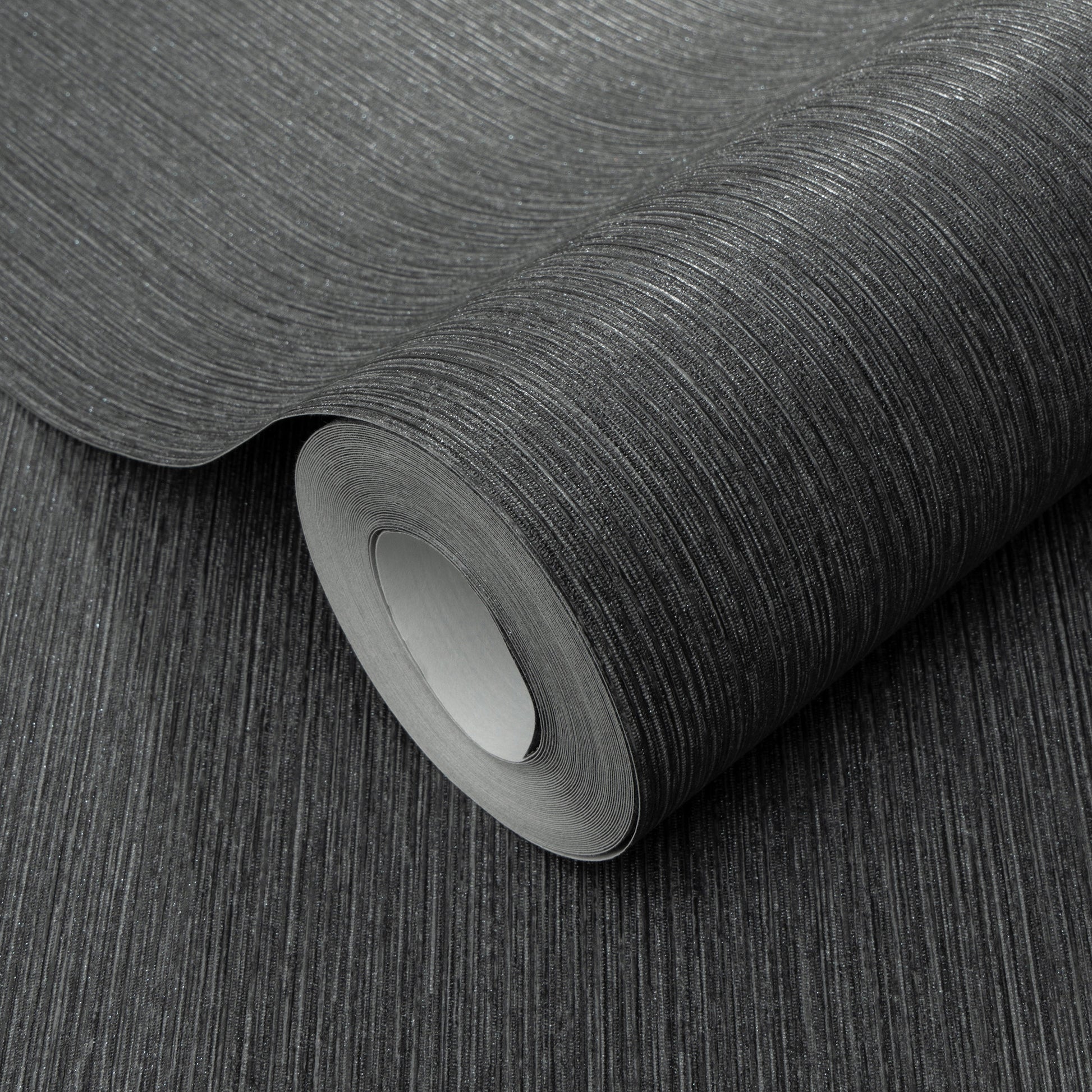 Charcoal textured wallpaper roll with subtle vertical linear grain, matte finish, partially unrolled for home decor.