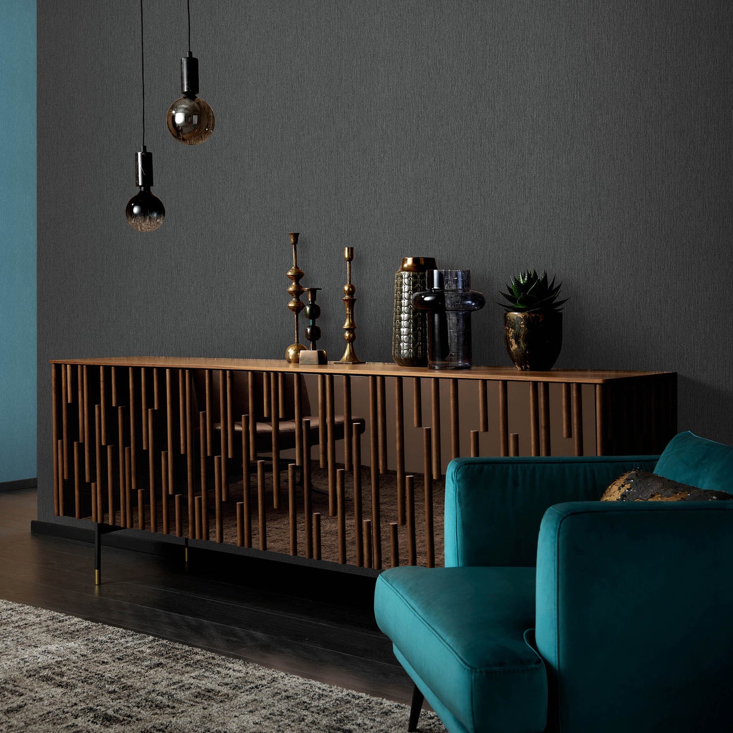 Wooden sideboard with vertical slats against a charcoal wall; brass candlesticks, books, plant on top, teal sofa in front.