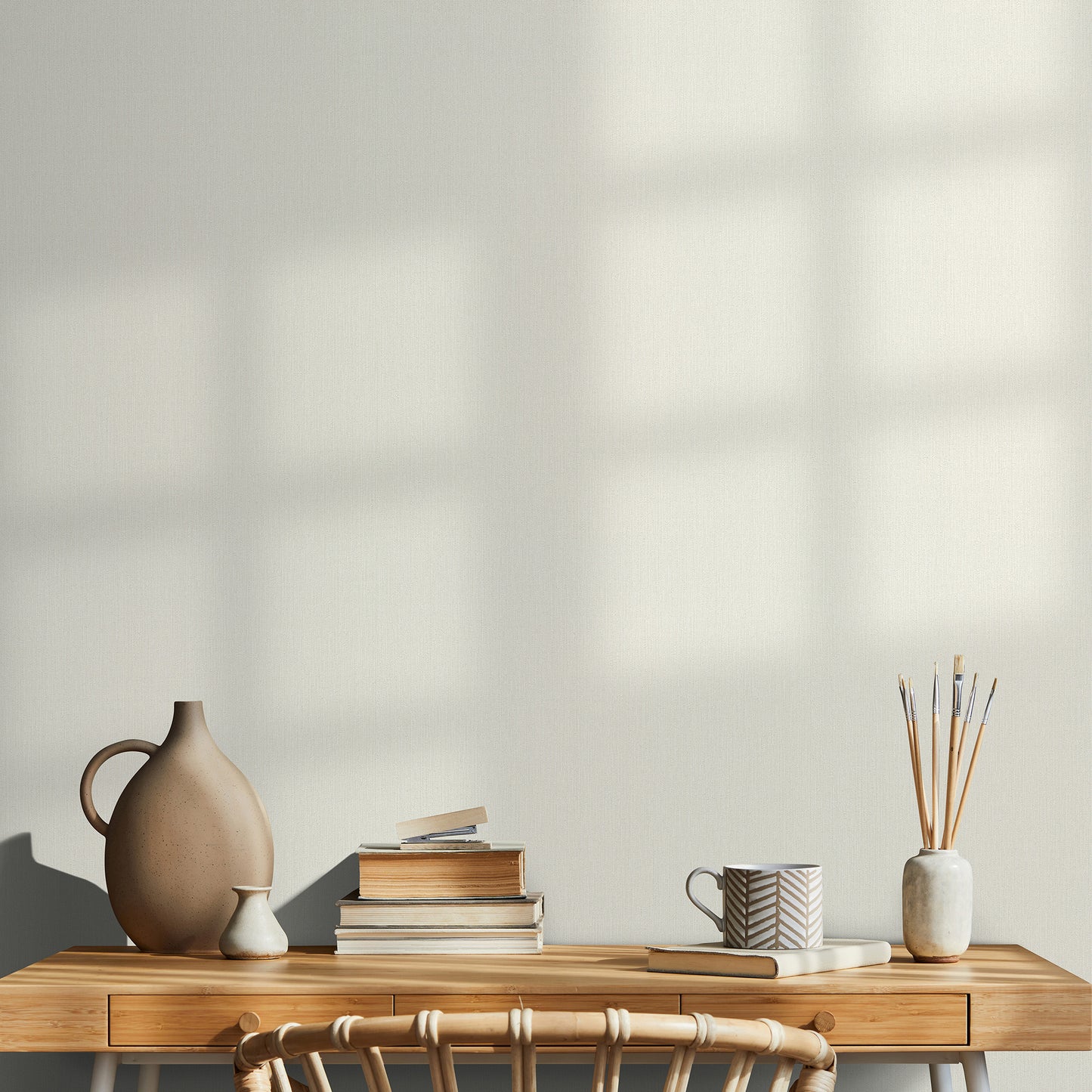 Wood desk with two drawers, ceramic brown vase, cream vase, stack of books, chevron-pattern mug, brushes in a ceramic jar.
