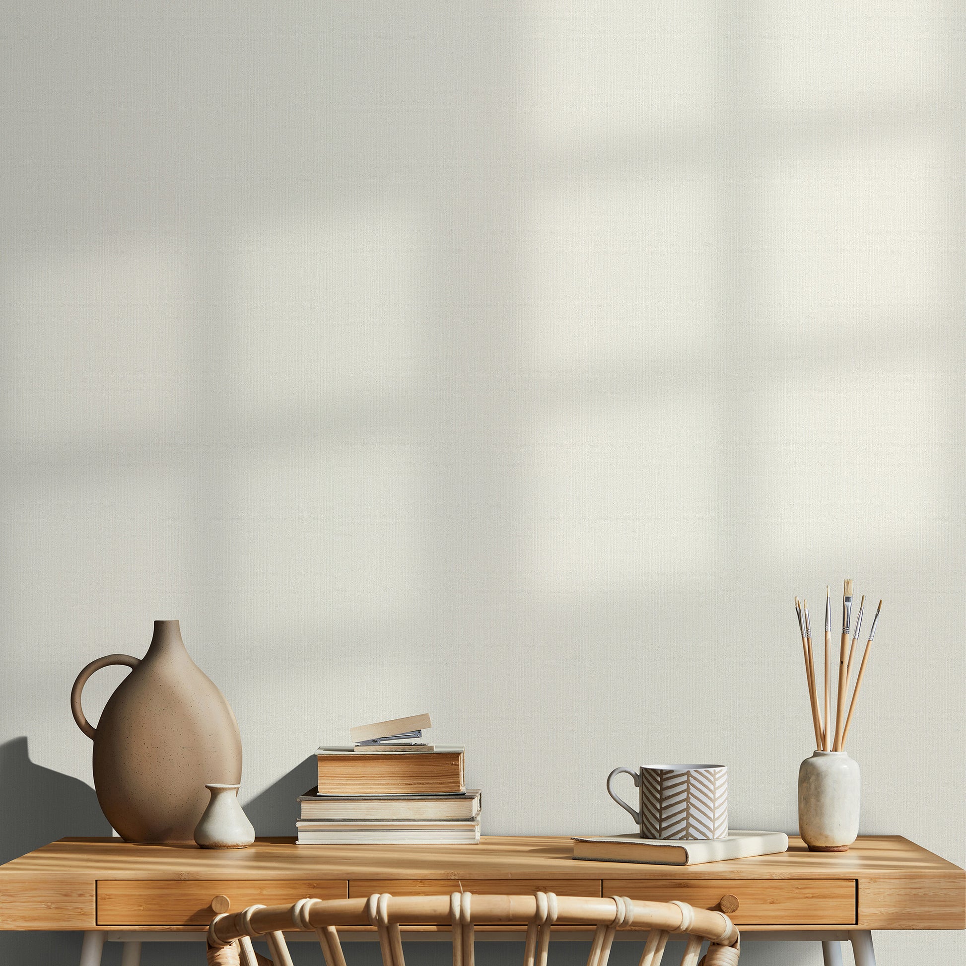 Wood desk with two drawers, ceramic brown vase, cream vase, stack of books, chevron-pattern mug, brushes in a ceramic jar.