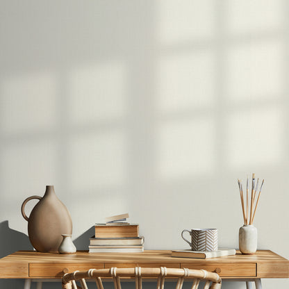 Wood desk with two drawers, ceramic brown vase, cream vase, stack of books, chevron-pattern mug, brushes in a ceramic jar.