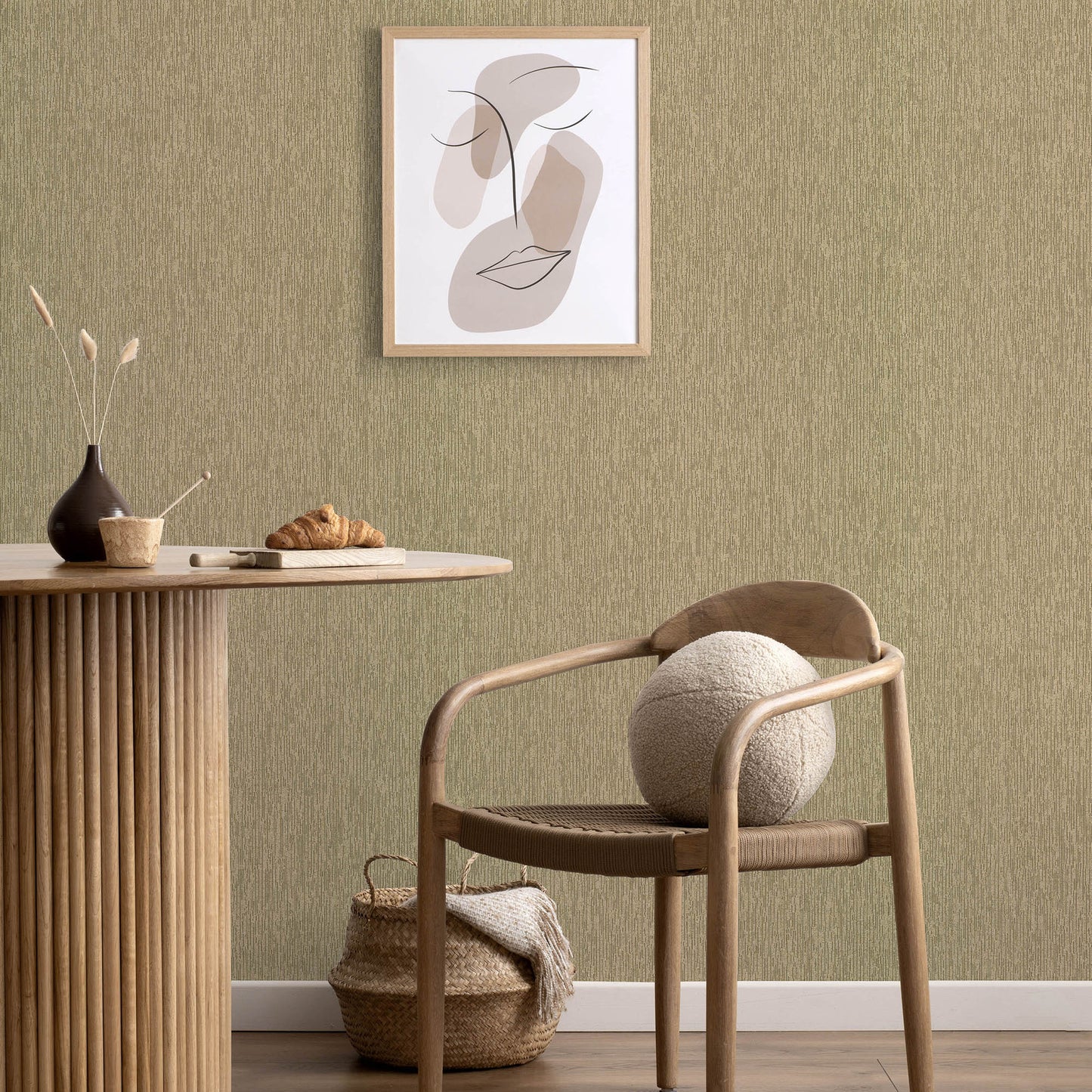 Natural wood round table with vertical-slat base, woven chair, wool ball, gold wallpaper with an abstract line art pattern.