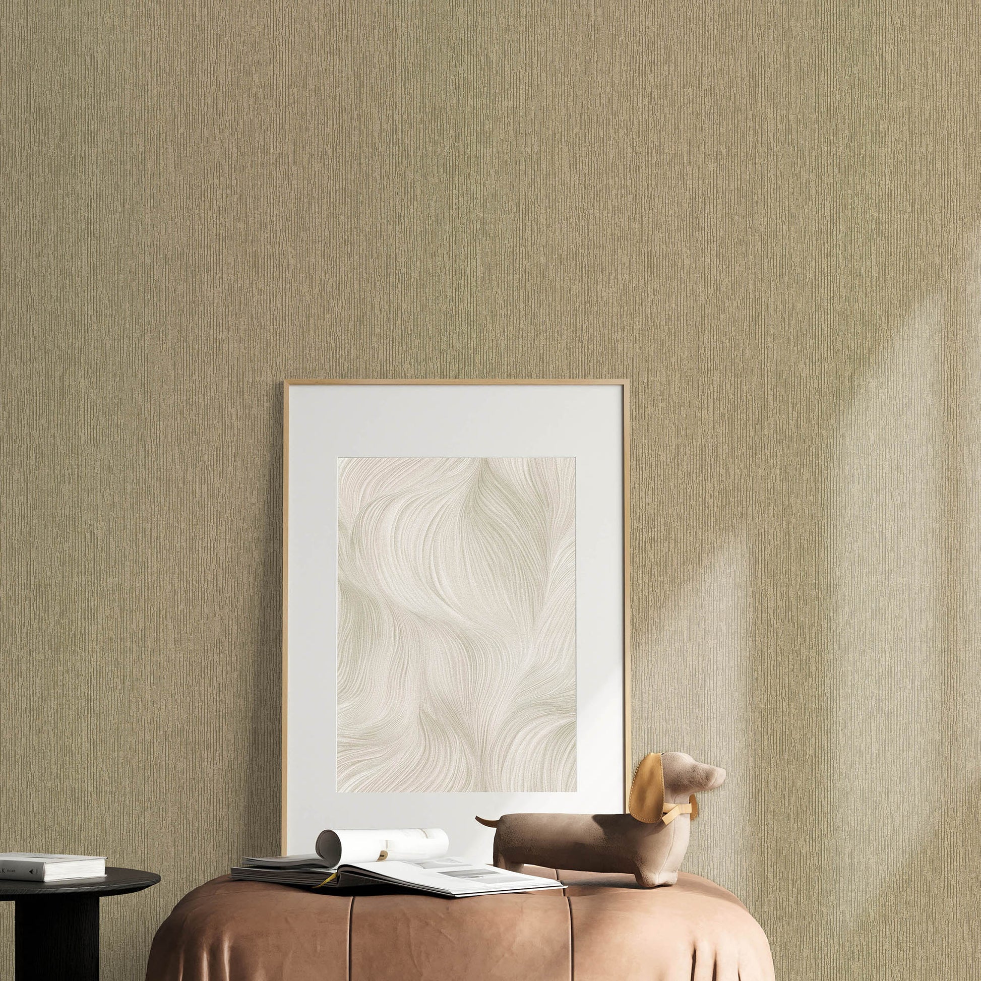 Beige textured wall with a gold-framed print, brown leather ottoman, magazines, rolled papers, and a tan dachshund sculpture.