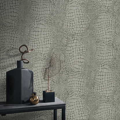 Matte black vase with curved metal loop, brass orb, blue-black cube, and geometric wire fan sculpture on a dark table against textured wallpaper.