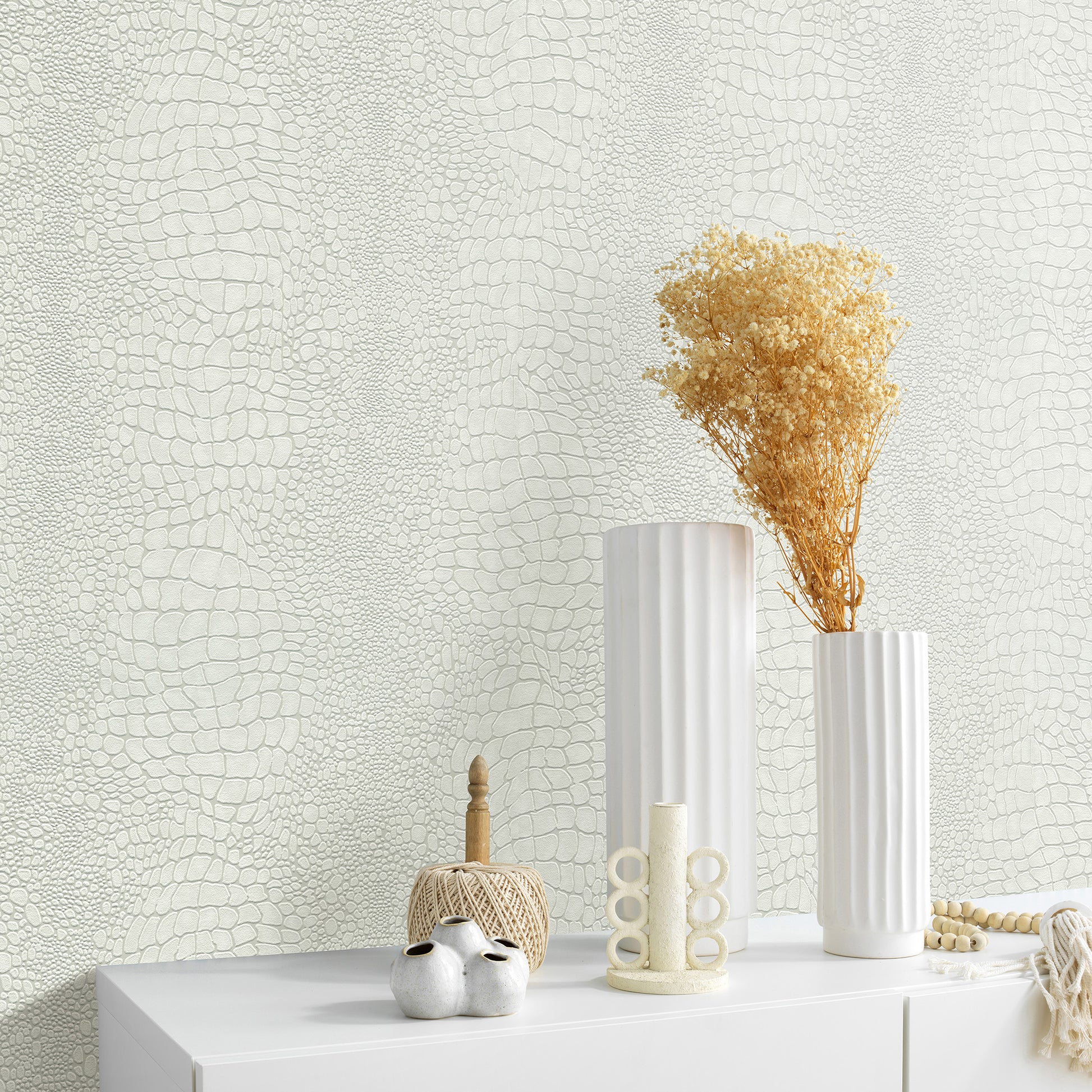 White ribbed ceramic vases with dried beige bouquet on a white tabletop, set against pale textured wallpaper.