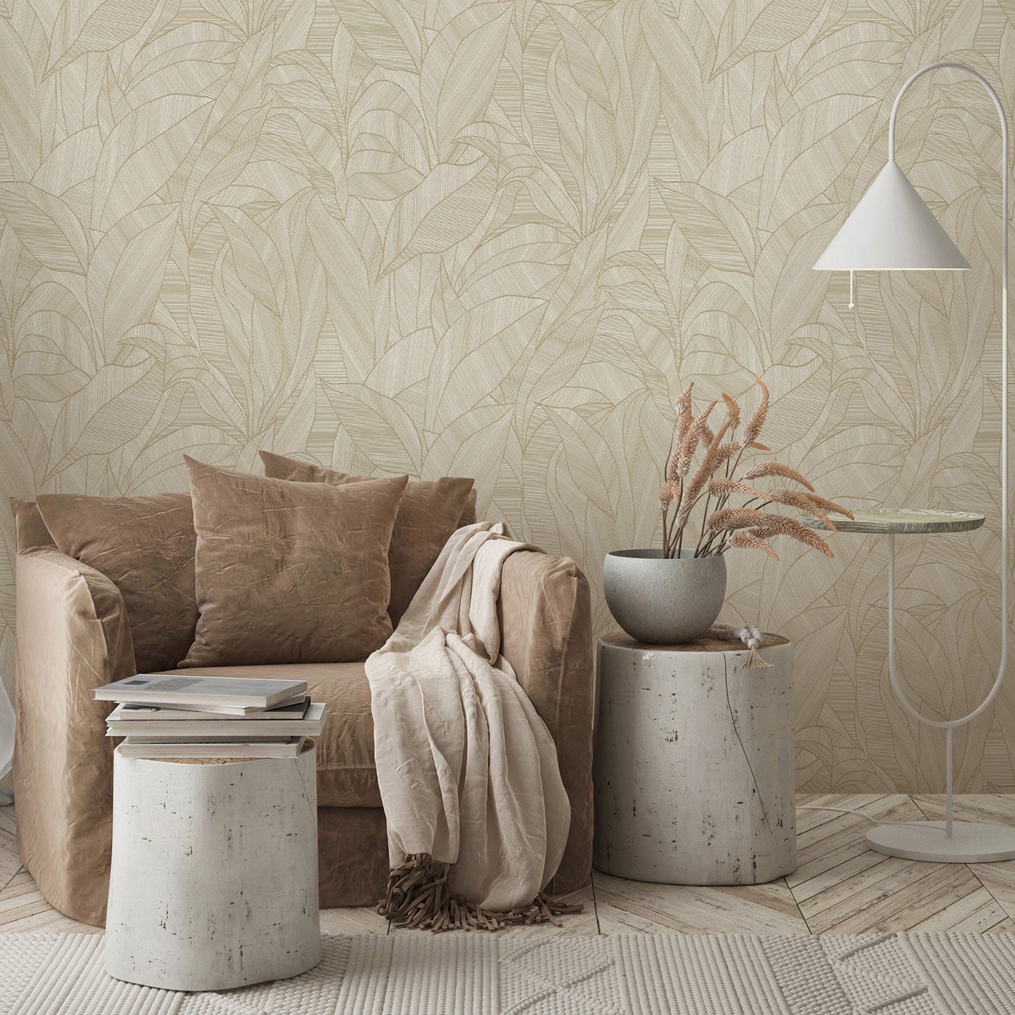 Beige sofa with cushions and throw, concrete stump tables, vase of dried grasses, white arc floor lamp, brown wallpaper with leaves in the background.