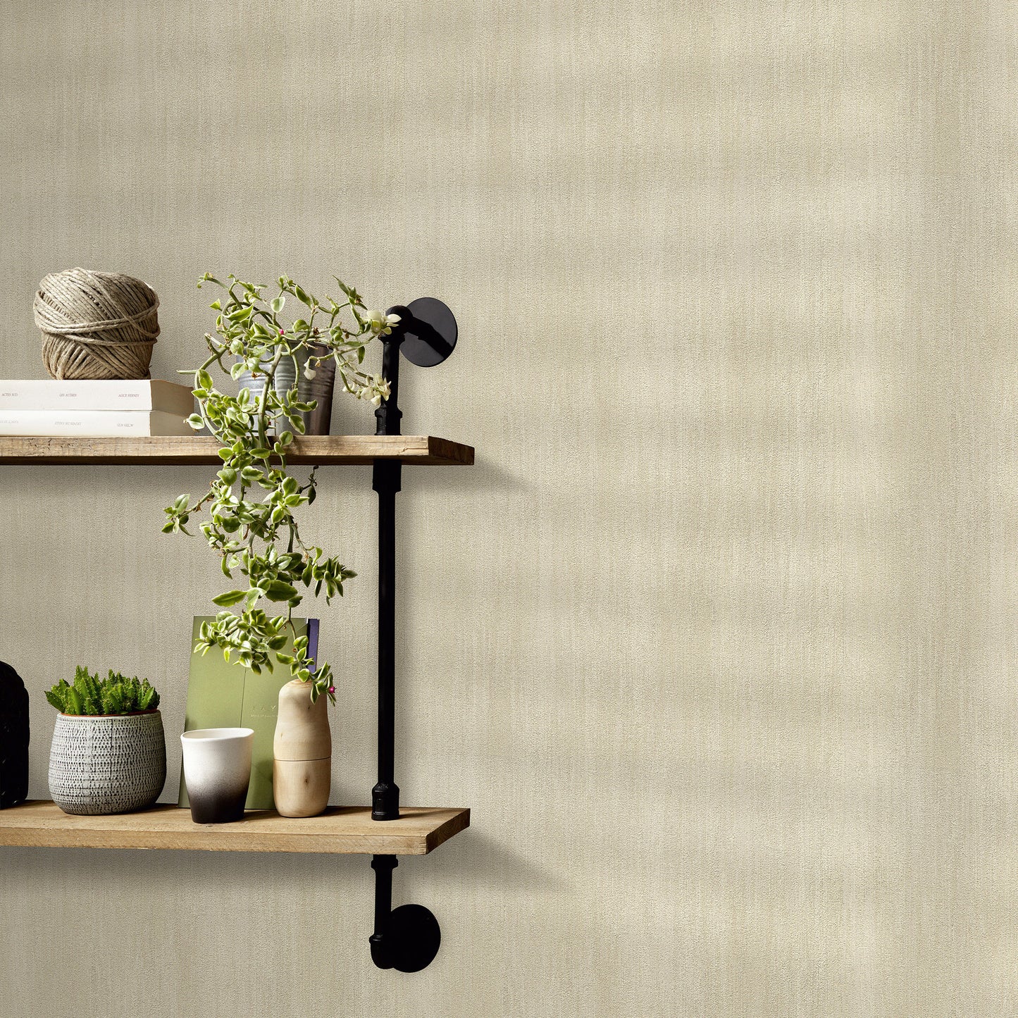 Beige textured wallpaper with raised pattern backdrop; two wooden shelves with black brackets, trailing plant, twine ball, books, small lamp, mugs and pots.