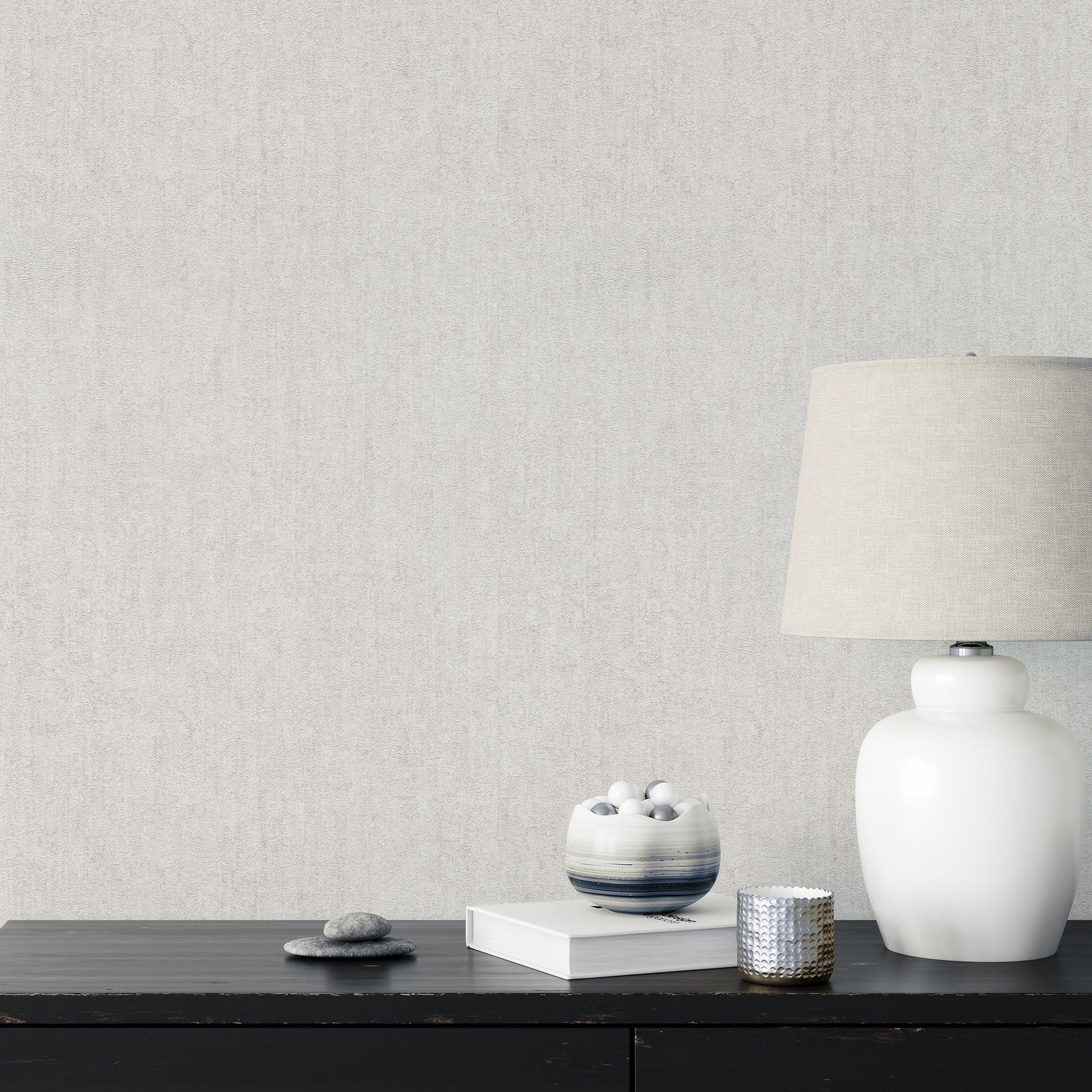 Cream textured wallpaper shown as a minimalist vignette with a dark wood dresser, white ceramic lamp with linen shade, blue-gray glazed bowl, and white spheres.