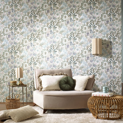 Blue floral wallpaper with a botanical pattern in sage, blue and beige; boho living room with a beige sofa, cushions, and a woven rattan coffee table.