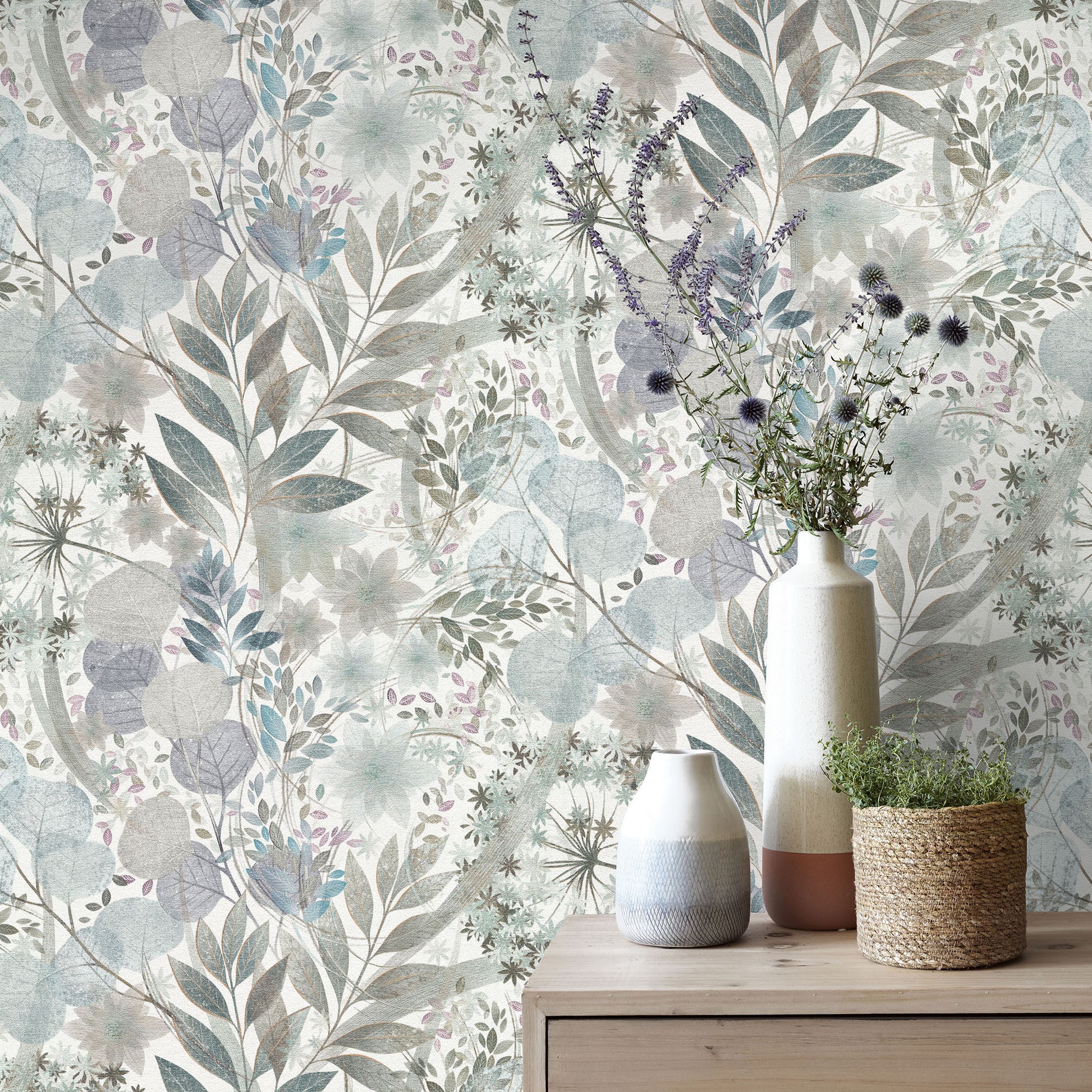 Pastel botanical wallpaper with blue-gray and sage leaves; wooden dresser displays ceramic vases and a woven planter.